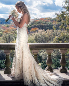 Bride smelling bouquet on a balcony with scenic hillside background
