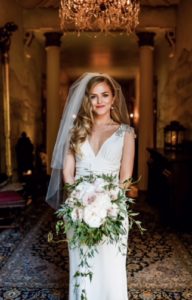 Bride with deep vintage waves, side part, red lipstick, bouquet and veil smiling at the camera