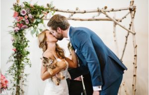 Bride with Yorkshire Terrier being kissed by groom